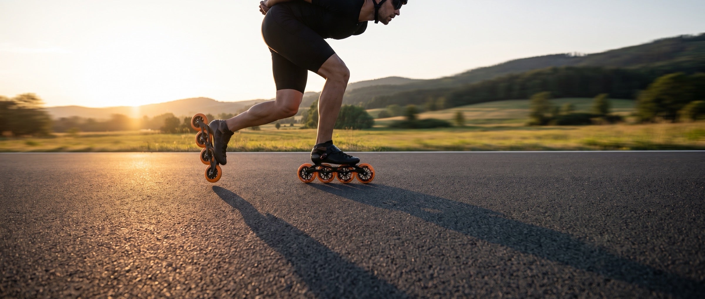 Speedskater mit orangen Rollen auf einer Landstraße bei Abendsonne